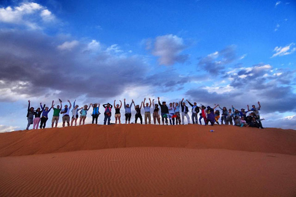 Grand groupe dans le désert de merzouga en photo souvenir. Ne manquez pas votre chance de voyager dans le désert au Maroc